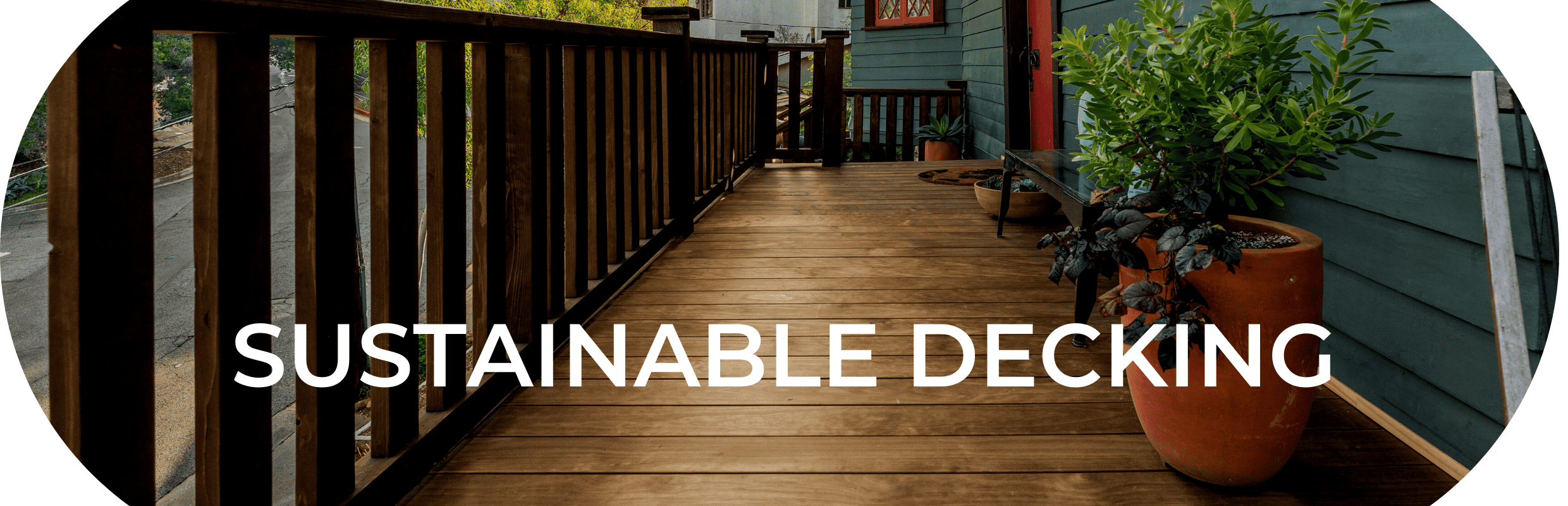 Image of a sustainable and healthy deck that spans the length of a teal colored home with a red door. The deck is made from Kebony Wood - a durable and beautiful modified wood decking.